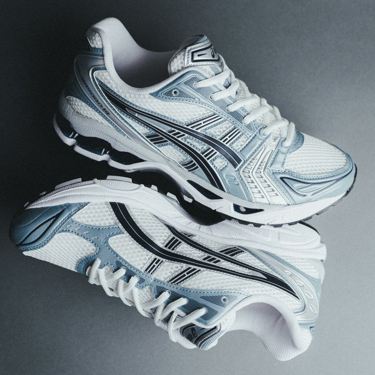 Pair of white and blue running shoes on a reflective surface with a dark background